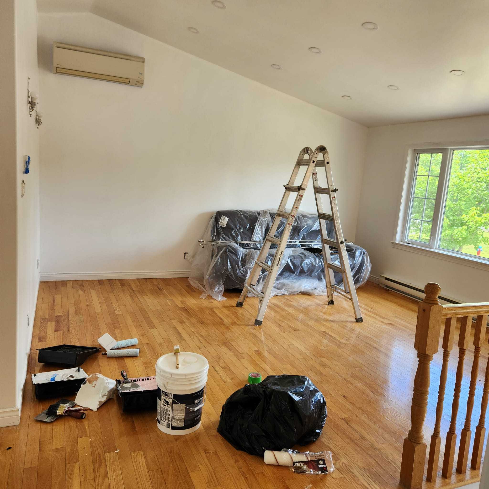 The room protected and being repainted with a ladder and painting supplies