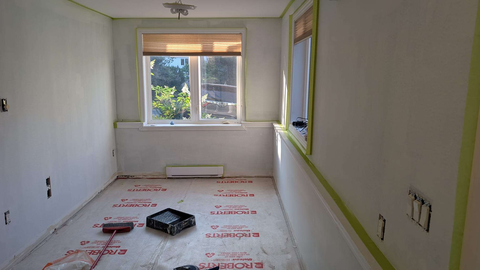 Room carefully prepared for painting with green tape around the trim and windows